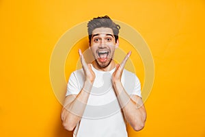 Photo of amazed man in basic clothing screaming in surprise or d