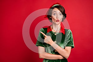Photo of amazed shocked woman santa helper elf point finger empty space sale holiday isolated on red color background