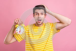 Photo of amazed shocked young man hold hands alarm clock late palm head isolated on pink color background