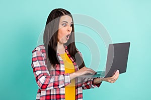 Photo of amazed shocked young woman hold look laptop unexpected news isolated on teal color background