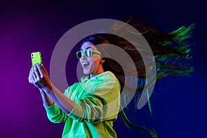 Photo of amazed shocked young woman look phone fast internet fly hair isolated on colorful neon background