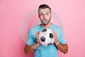 Photo of amazed surprised man in stupor holding soccer ball with hands loving to play football isolated pastel color