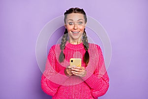 Photo of amazed surprised young woman hold phone like reaction happy isolated on purple color background