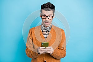 Photo of amazed young man stare stupor phone wear sweater hold smartphone isolated on blue color background