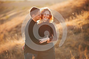 Photo of amazing cheerful couple embracing outdoor in sun light during sunset