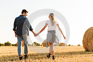 Photo of amazing couple man and woman walking through golden fie
