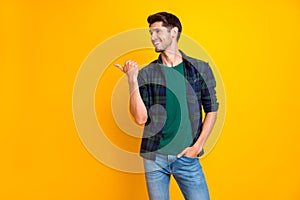 Photo of amazing guy indicating thumb finger to empty space wear casual plaid shirt and jeans isolated yellow color