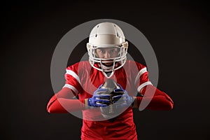 Photo of american female football player in helmet with rugby ball in hands