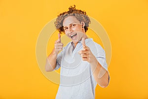 Photo of amusing handsome man 20s smiling and pointing fingers a