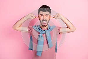 Photo of angry annoyed young man close fingers ears loud noise isolated on pastel pink color background