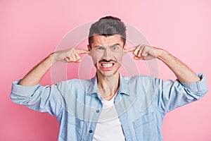 Photo of angry irritated unhappy guy close fingers ears loud noise isolated on pink color background