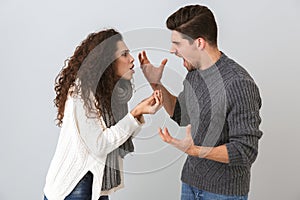 Photo of angry man and woman screaming at each other standing face to face, isolated over gray background