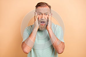 Photo of anxious embarrassed man open mouth touch face panic stupor fear isolated on beige color background