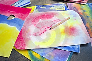 A photo of the artistic hand drawn abstract wet watercolor background, waldorf colorful template and a pencil. A lesson of drawing