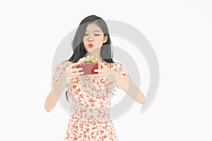 Photo of asian curious woman in red dress rejoicing her birthday or new year gift box. Young woman holding gift  box with red bow