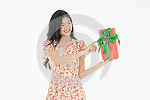 Photo of asian curious woman in red dress rejoicing her birthday or new year gift box. Young woman holding gift  box with red bow