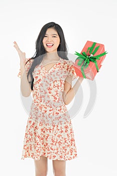 Photo of asian curious woman in red dress rejoicing her birthday or new year gift box. Young woman holding gift  box with red bow