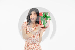 Photo of asian curious woman in red dress rejoicing her birthday or new year gift box. Young woman holding gift  box with red bow