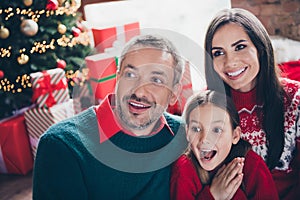 Photo of astonished little girl parents look interested unbelievable reaction newyear tree lights decor flat indoors