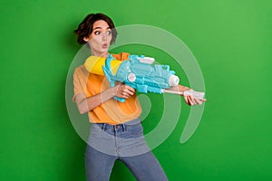 Photo of astonished positive person arms hold pump water weapon look empty space isolated on green color background