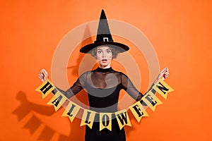 Photo of astonished pretty lady hands hold halloween flags isolated on orange color background
