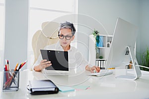 Photo of attentive serious lady expert dressed white shirt holding documents typing modern gadget indoors workstation
