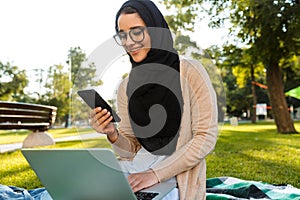 Photo of attractive arabic woman wearing headscarf using silver laptop