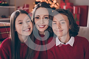 Photo of attractive cute mom son daughter wear red pullovers smiling celebrating christmas hugging indoors house home