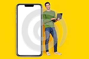 Photo of attractive cute young guy wear green sweater working modern device empty space isolated yellow color background