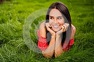 Photo of attractive dreamy stunning brunette woman hold hands cheeks lie grass look park outside in outdoors