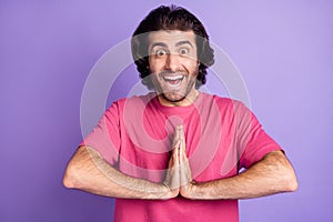 Photo of attractive excited young man wear pink t-shirt ask buy new things arms together isolated violet color