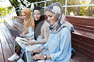 Photo of attractive islamic women wearing headscarfs resting in green park