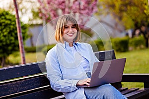 Photo of attractive lady student sit on bench in green park browsing notebook chatting friends do home tasks inspiration nature