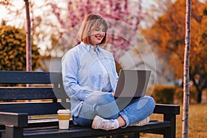 Photo of attractive lady student sit on bench in green park browsing notebook chatting friends do home tasks inspiration nature