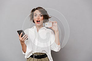 Photo of attractive woman 20s holding mobile phone and credit ca