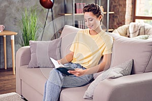 Photo of attractive young happy woman sit sofa read book weekend hobby indoors inside house home flat