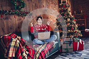 Photo of attractive young woman sit sofa netbook raise fists dressed red sweater christmas room interior design tree