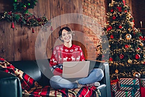 Photo of attractive young woman sit sofa netbook toothy smile dressed red sweater christmas room interior design tree