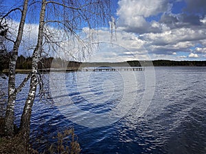 Photo of autumn nature. View of the pier and a deep lake with dry reeds. Overcast sky