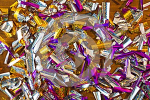 Photo background of rectangular confetti made of purple and gold foil on the wooden background