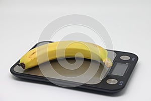 photo of the banana at electronic scales against the white background.