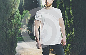 Photo Bearded Muscular Man Wearing White Blank t-shirt. Green Garden outdoor Background and Sunlight effect. Horizontal