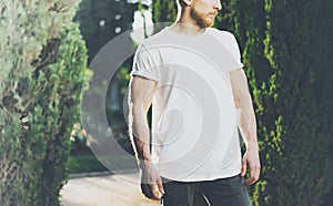 Photo Bearded Muscular Man Wearing White Blank t-shirt. Green Park outdoor Background and Sunlight effect. Horizontal