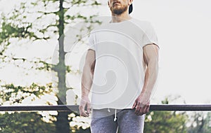 Photo Bearded Muscular Man Wearing White Blank t-shirt, snapback cap and shorts in summer vacation. Relaxing time near