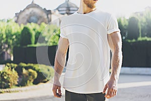 Photo Bearded Muscular Man Wearing White Blank t-shirt. in summer time. Green City Garden Background at sunset