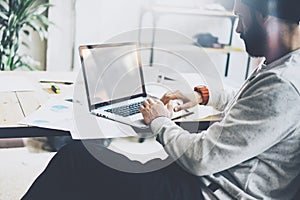 Photo bearded project manager working new startup modern loft. Using contemprary laptop with reflections screen on wood