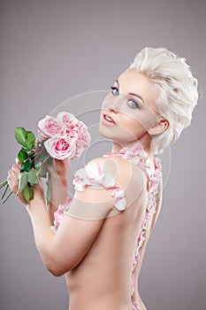 Photo of a beautiful blond woman with flower. Closeup attractive sensual face of white woman with curly hair. Smokey eye