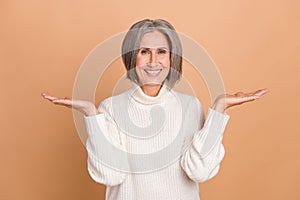 Photo of beautiful charming attractive positive pensioner woman hold arms choose best deal empty space promo isolated on