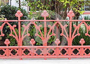 Photo of a Beautiful decorative vintage cast iron wrought fence with artistic forging. Metal guardrail close up with garden