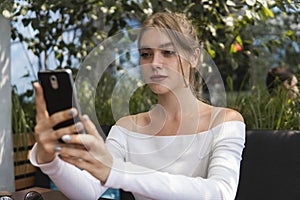 Photo of beautiful lady sitting in cafe and making selfie with a smart phone. Portrait of young smiling student girl